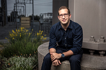 A man with glasses sitting on the edge of a utility power station