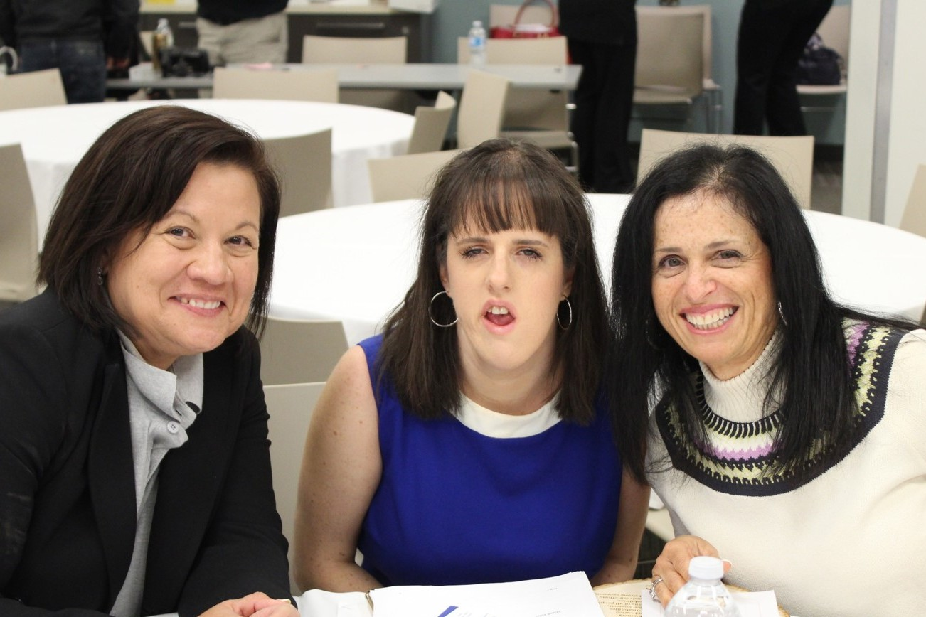 Three ladies smiling seated at a table