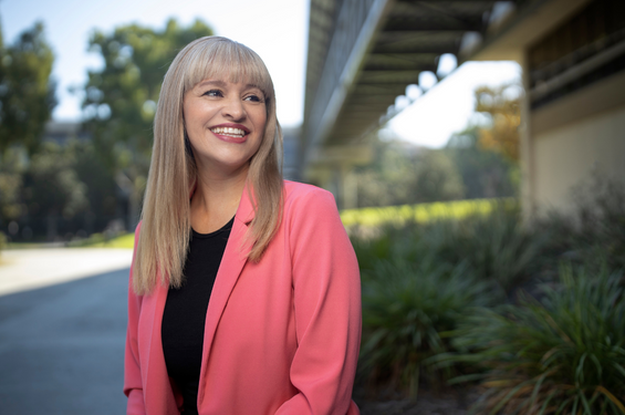 A woman smiling off to the side in a pink blazer