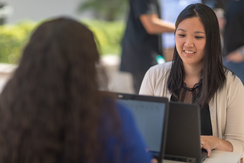 Two women sitting across from each other working on their laptop