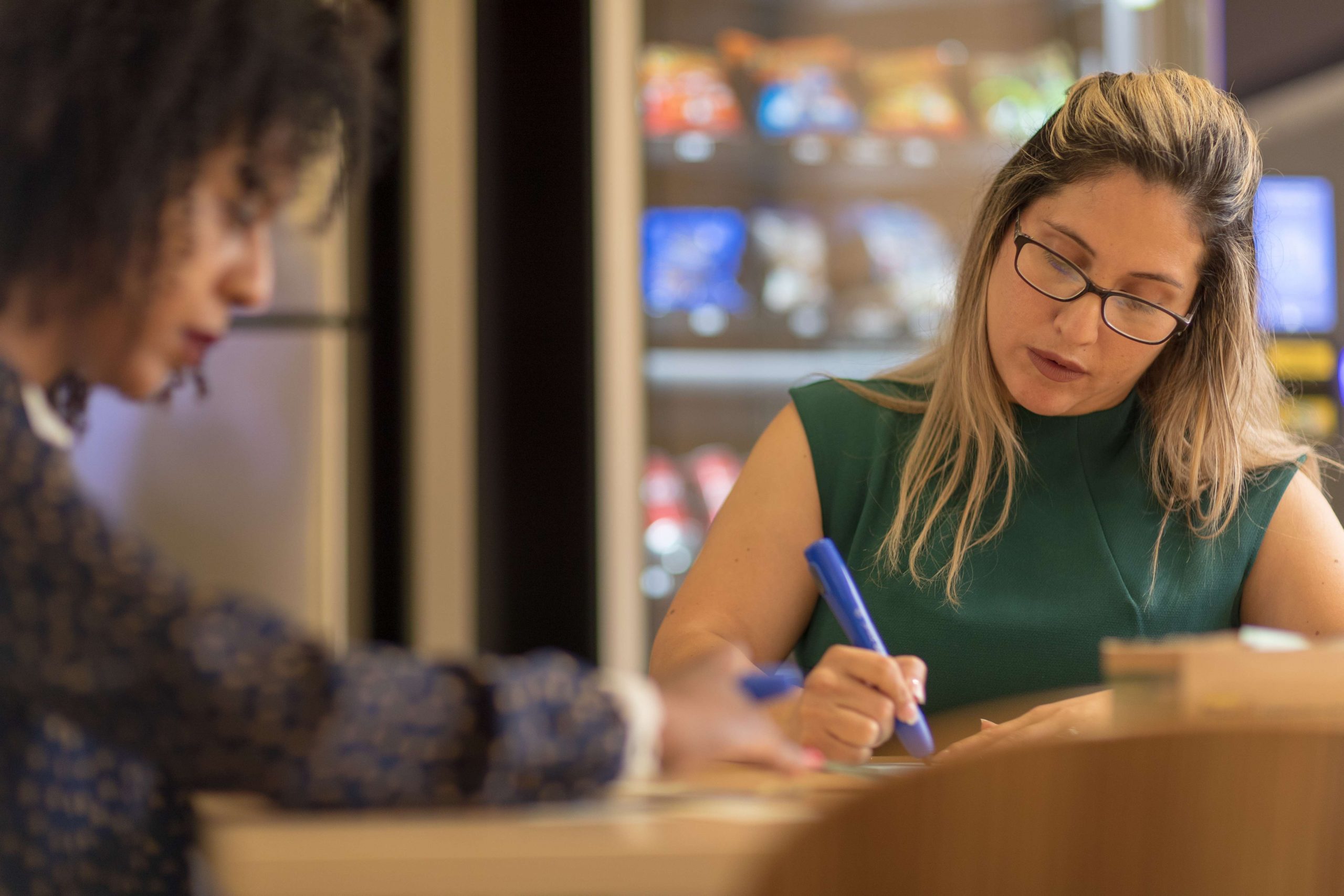 two women working at a desk with large markers