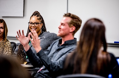 A man sitting with peers, using his hands to describe