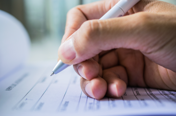 A hand holding a pen and writing on an application