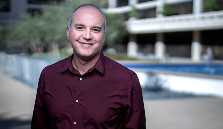 A man in a burgundy shirt smiling at the camera
